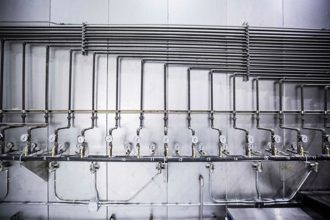 about-01 Detailed view of an industrial plumbing system featuring multiple pressure gauges and steel pipes.
